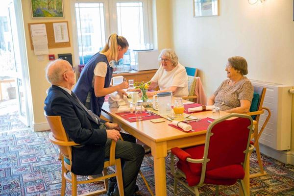 Residents sitting around the table waiting for their meal at Abbeyfield House
